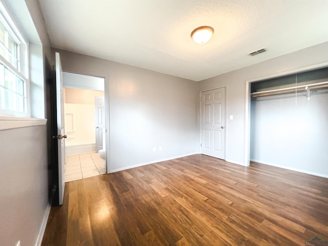 unfurnished bedroom featuring a textured ceiling, hardwood / wood-style flooring, and a closet