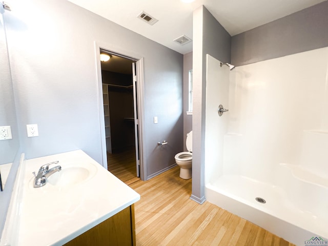 bathroom with a shower, vanity, hardwood / wood-style flooring, and toilet