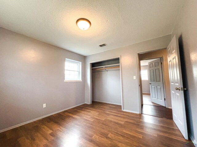 unfurnished bedroom with a closet, dark wood-type flooring, and a textured ceiling