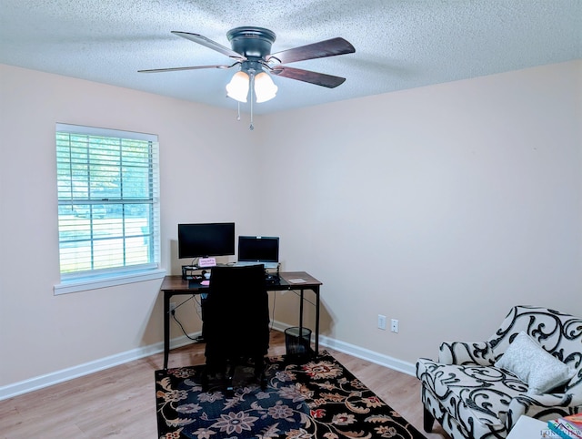 office featuring a textured ceiling, ceiling fan, baseboards, and light wood-type flooring