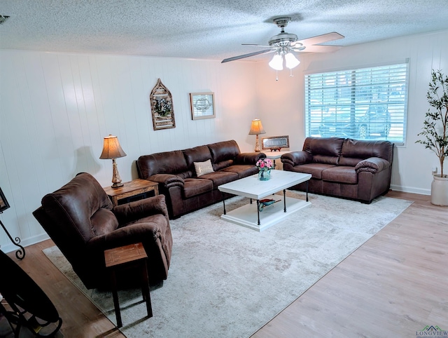 living area with a textured ceiling, ceiling fan, and wood finished floors