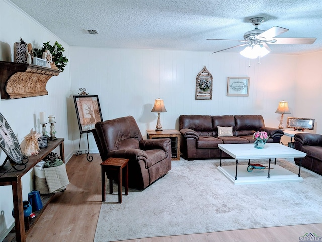 living room featuring visible vents, a ceiling fan, a textured ceiling, and wood finished floors
