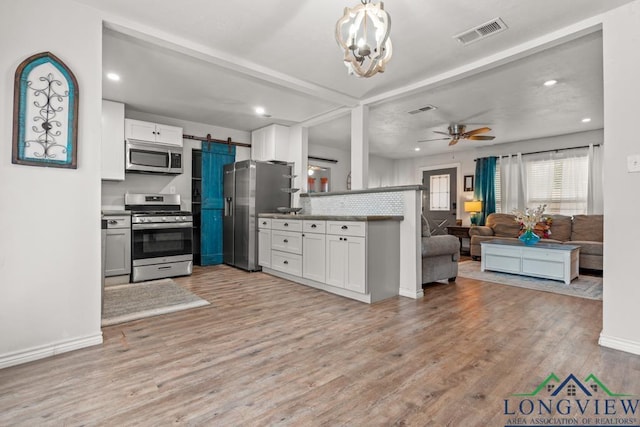 718 Pine St, Gilmer, TX 75644 - kitchen with light wood finished floors, visible vents, open floor plan, white cabinets, and appliances with stainless steel finishes