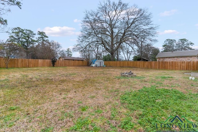 718 Pine St, Gilmer, TX 75644 - view of yard with a fenced backyard, an outdoor structure, a fire pit, and a storage unit