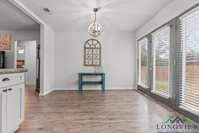 718 Pine St, Gilmer, TX 75644 - unfurnished dining area featuring a chandelier, light wood-style flooring, baseboards, and visible vents