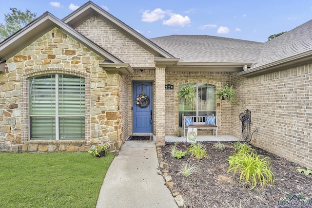 220 Cedar Rdg, Longview, TX 75602 - view of exterior entry featuring a shingled roof, stone siding, brick siding, a porch, and a lawn