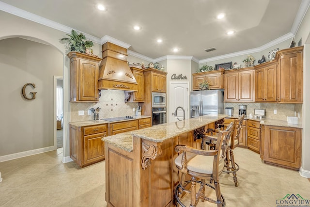 220 Cedar Rdg, Longview, TX 75602 - kitchen featuring light stone counters, arched walkways, an island with sink, stainless steel appliances, and custom range hood