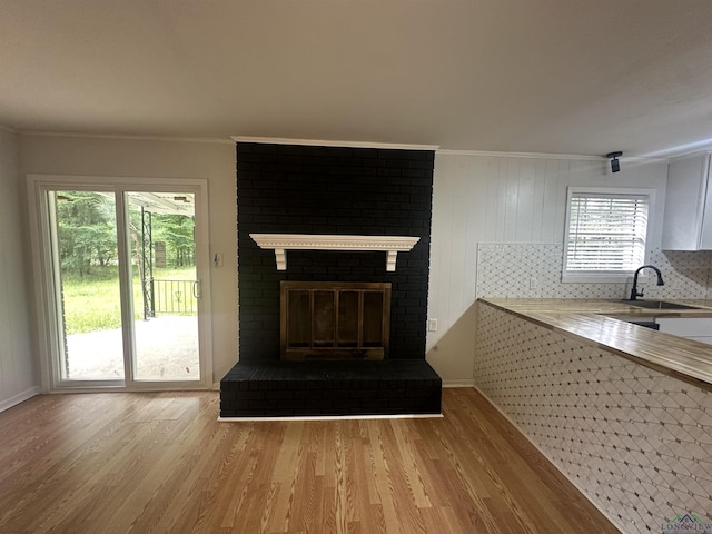 3401 Cooper Ln, Texarkana, TX 75503 - unfurnished living room featuring a sink, light wood-style floors, crown molding, a fireplace, and baseboards