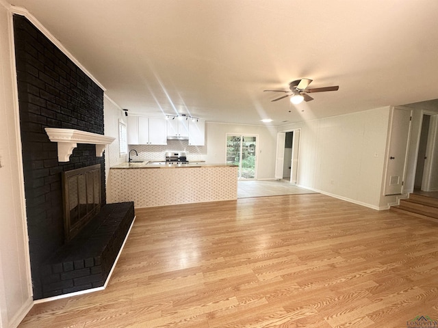 3401 Cooper Ln, Texarkana, TX 75503 - unfurnished living room featuring light wood-type flooring, ceiling fan, plenty of natural light, and a brick fireplace