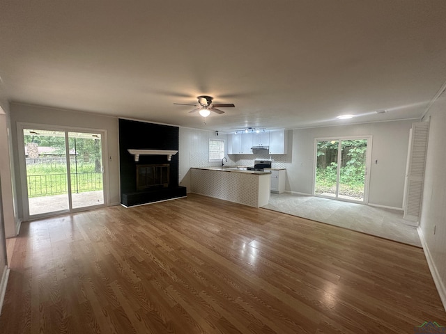 3401 Cooper Ln, Texarkana, TX 75503 - unfurnished living room with ceiling fan, light wood-style flooring, a glass covered fireplace, and healthy amount of natural light