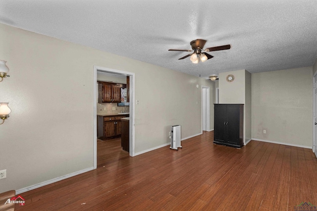 unfurnished living room with ceiling fan, dark hardwood / wood-style flooring, and a textured ceiling