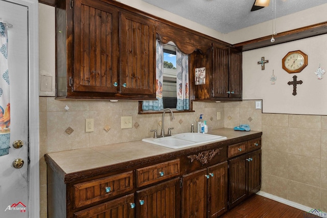 kitchen with ceiling fan, sink, dark hardwood / wood-style flooring, a textured ceiling, and dark brown cabinets