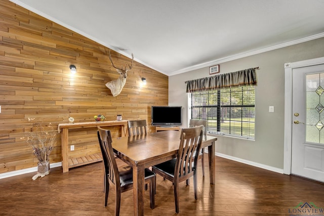 dining space featuring dark hardwood / wood-style flooring, crown molding, wooden walls, and vaulted ceiling