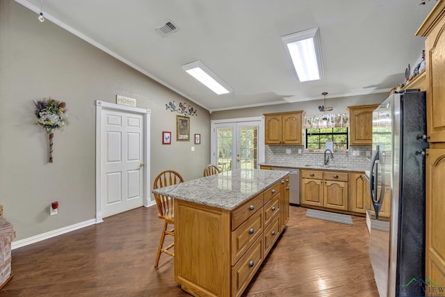 kitchen featuring dark wood-type flooring, tasteful backsplash, decorative light fixtures, a kitchen island, and appliances with stainless steel finishes