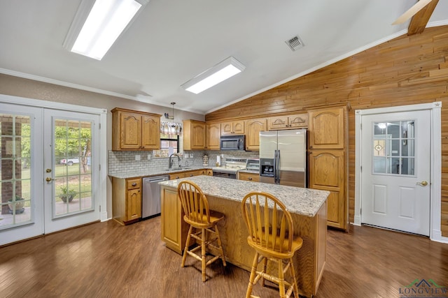 kitchen featuring french doors, hanging light fixtures, vaulted ceiling, a kitchen island, and stainless steel appliances