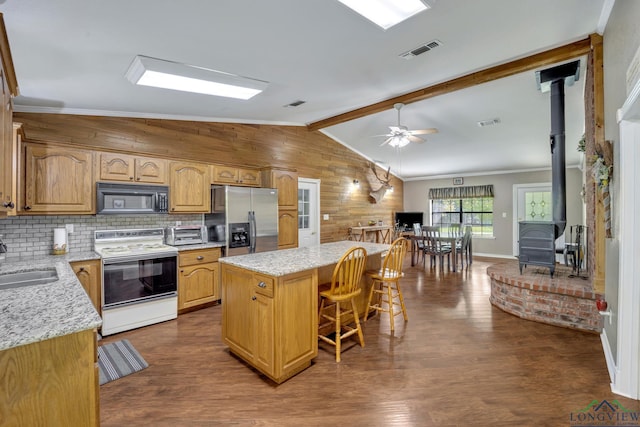 kitchen featuring a wood stove, a kitchen breakfast bar, stainless steel fridge with ice dispenser, white range with electric cooktop, and a kitchen island