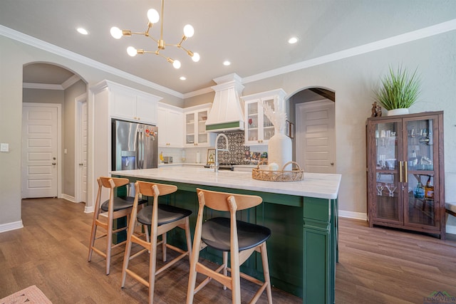 kitchen featuring crown molding, hardwood / wood-style flooring, a large island, white cabinetry, and stainless steel fridge with ice dispenser