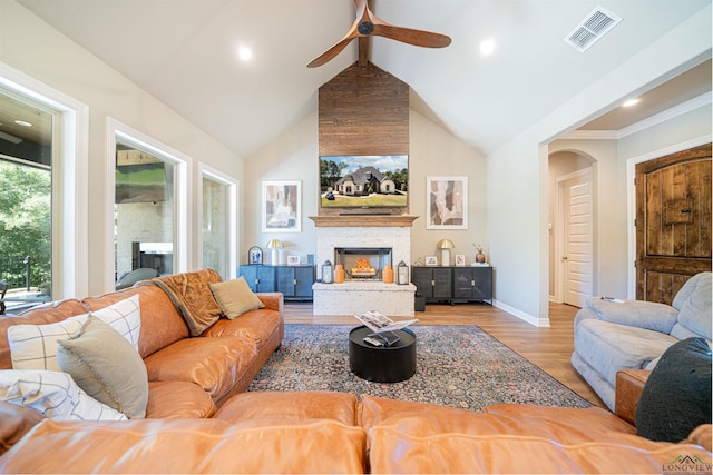 living room featuring ceiling fan, vaulted ceiling, a fireplace, and light hardwood / wood-style flooring