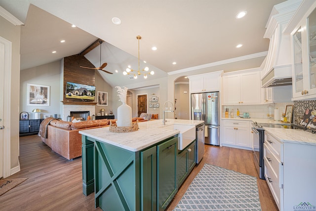 kitchen featuring tasteful backsplash, stainless steel appliances, a kitchen island with sink, white cabinetry, and hanging light fixtures