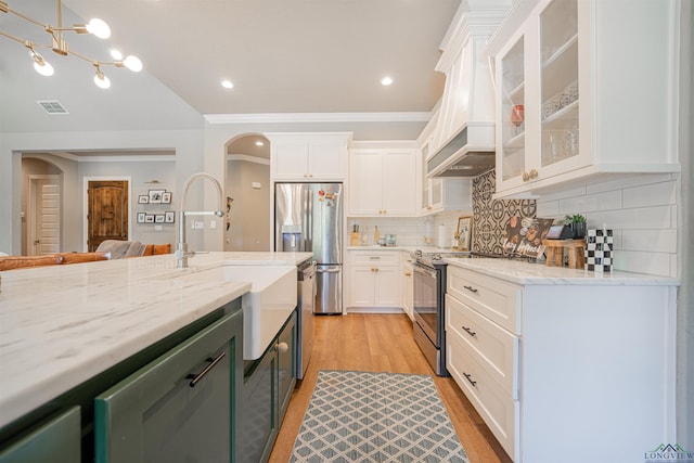 kitchen with white cabinets, appliances with stainless steel finishes, tasteful backsplash, and light stone countertops