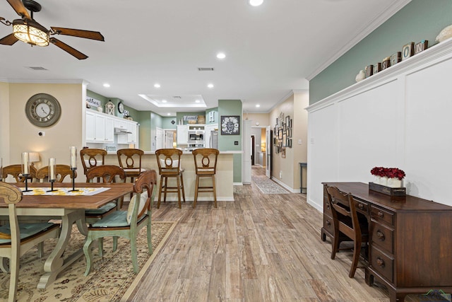 dining space with light hardwood / wood-style floors, ceiling fan, and crown molding