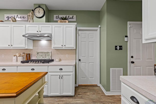 kitchen featuring white cabinets, stainless steel gas cooktop, backsplash, and light hardwood / wood-style flooring