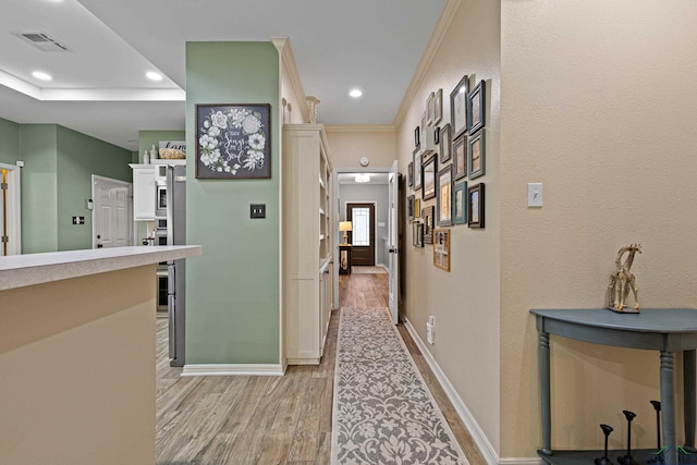 hallway with light hardwood / wood-style flooring and crown molding