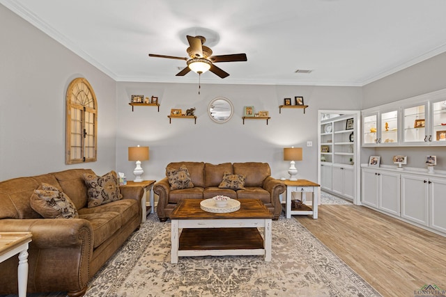 living room featuring ornamental molding, ceiling fan, and light wood-type flooring