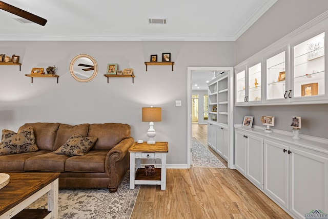 living room with built in features, ceiling fan, ornamental molding, and light hardwood / wood-style flooring