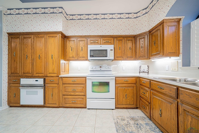 kitchen with light tile patterned floors, white appliances, and sink