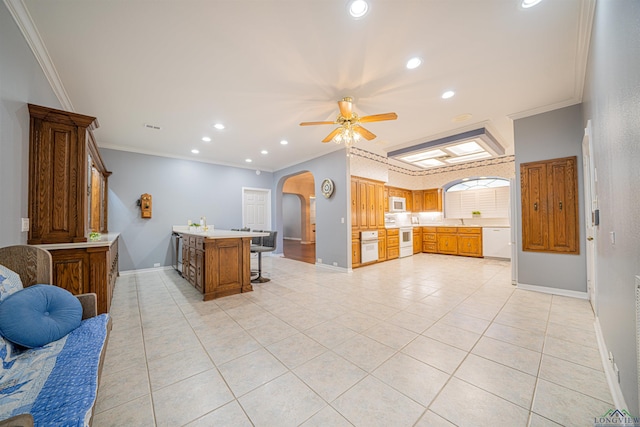 kitchen featuring ornamental molding, white appliances, ceiling fan, light tile patterned floors, and a breakfast bar area