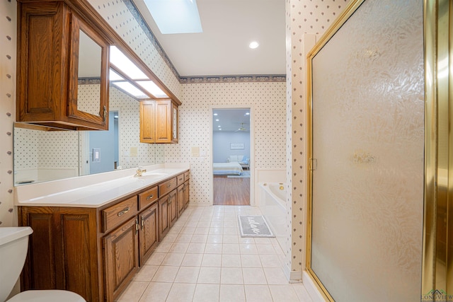 bathroom featuring tile patterned flooring, shower with separate bathtub, vanity, and a skylight