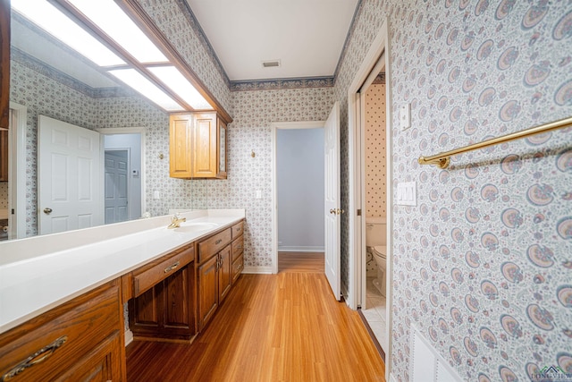 bathroom with hardwood / wood-style floors, vanity, toilet, and ornamental molding