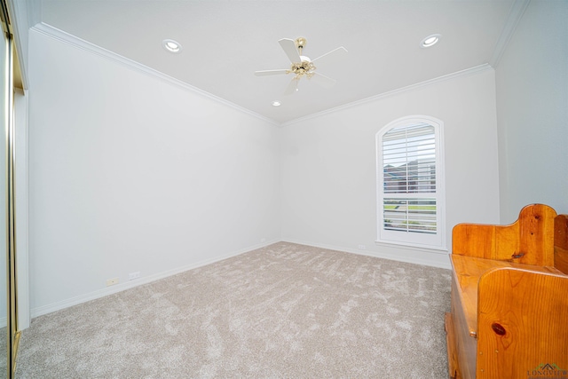 carpeted spare room with ceiling fan and ornamental molding