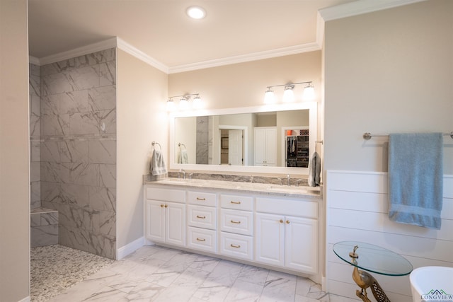 full bath featuring a wainscoted wall, marble finish floor, a tile shower, double vanity, and crown molding