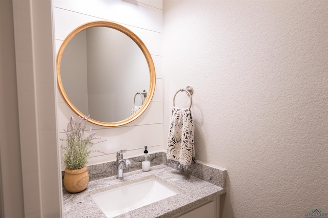 bathroom featuring a textured wall and vanity