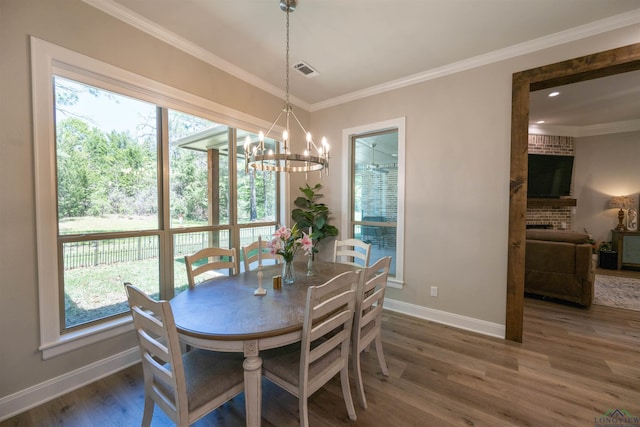 dining space featuring a healthy amount of sunlight, crown molding, visible vents, and wood finished floors