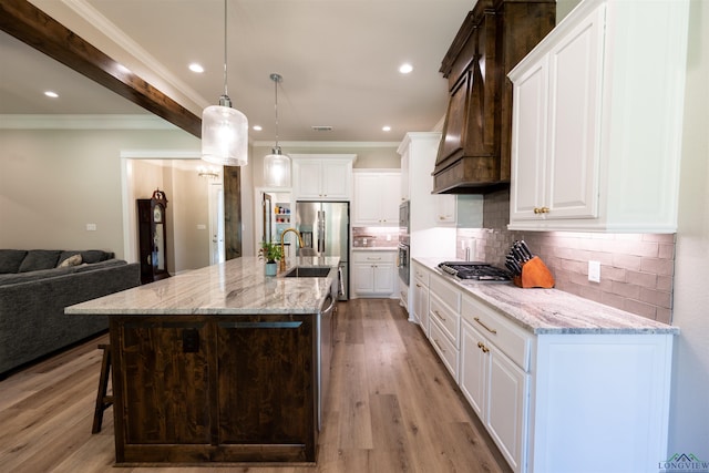 kitchen with tasteful backsplash, appliances with stainless steel finishes, ornamental molding, a sink, and light wood-type flooring