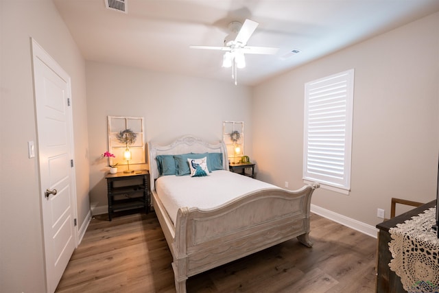 bedroom with ceiling fan, wood finished floors, and baseboards