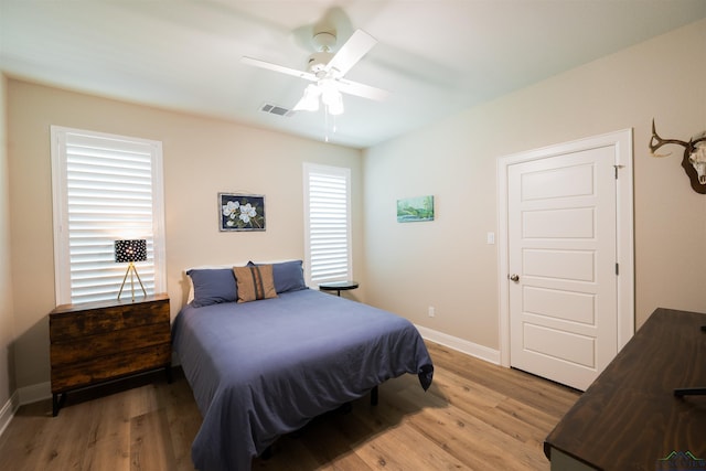 bedroom featuring light wood finished floors, baseboards, visible vents, and ceiling fan