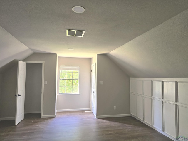 2013 E Warwick Cir, Longview, TX 75601 - additional living space featuring vaulted ceiling, a textured ceiling, and dark wood finished floors