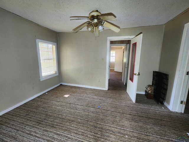 empty room with ceiling fan, dark carpet, and a textured ceiling