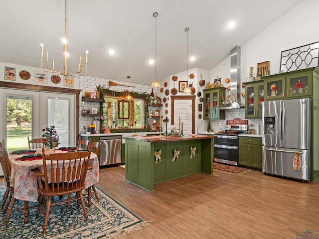 kitchen featuring decorative backsplash, a kitchen island, wall chimney range hood, and appliances with stainless steel finishes