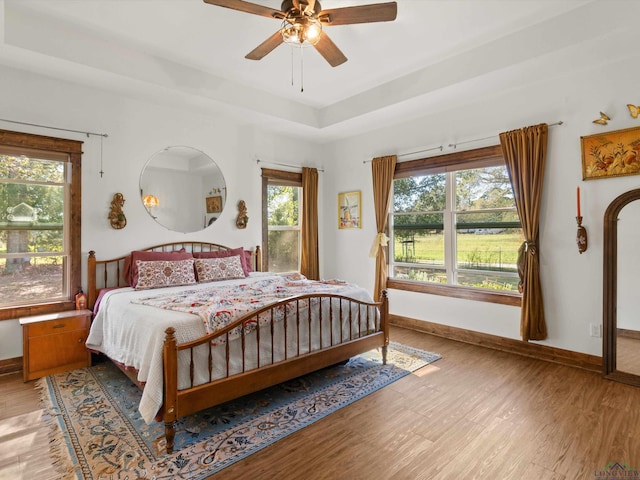 bedroom featuring hardwood / wood-style floors, a raised ceiling, and ceiling fan