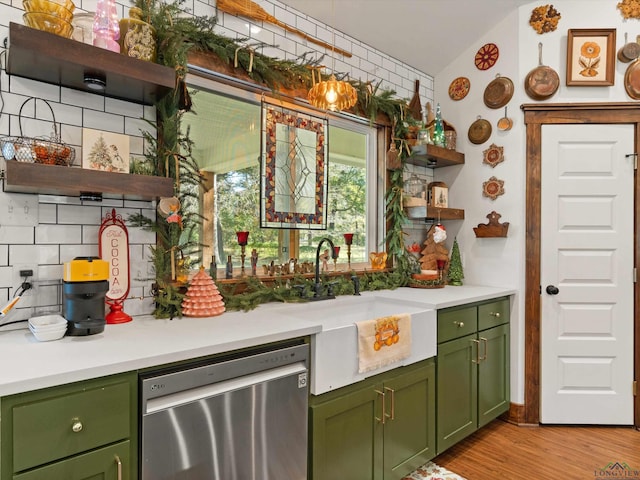 bar featuring sink, green cabinets, stainless steel dishwasher, decorative backsplash, and light wood-type flooring