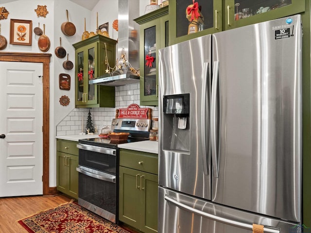 kitchen with backsplash, green cabinets, extractor fan, and appliances with stainless steel finishes