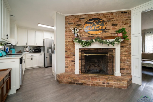 kitchen with a sink, wood finished floors, white cabinetry, stainless steel appliances, and light countertops