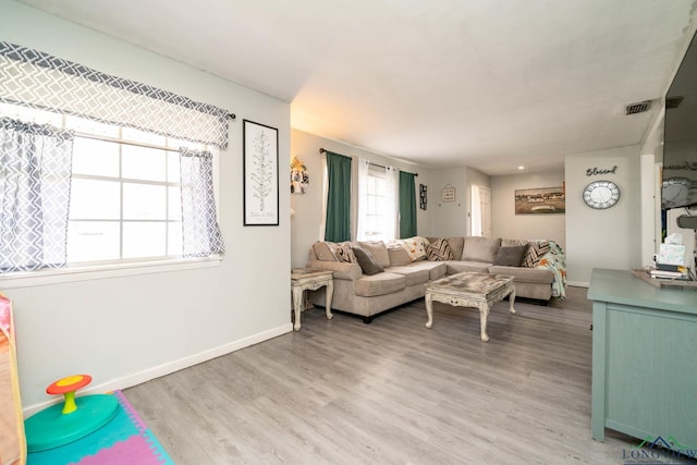 living room with visible vents, baseboards, and light wood-style flooring