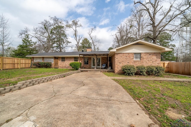 ranch-style house featuring a front yard, a porch, fence, and brick siding