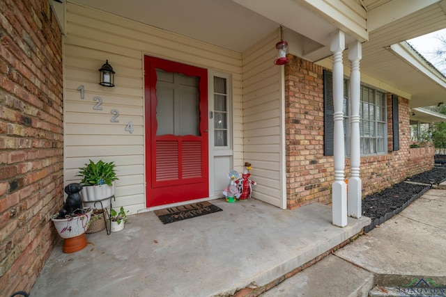 property entrance with a porch and brick siding